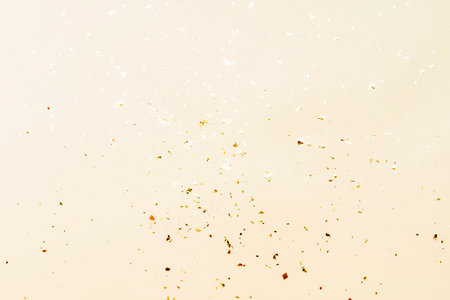 Shiny golden confetti on beige background, texture. Holidays concept.の写真素材
