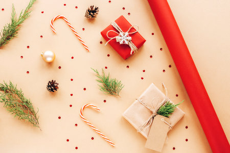 Gift boxes, candy canes and cypress branches. Christmas preparation of gifts with red and beige wrapping paper. New Year concept. Top view, flat lay.の写真素材
