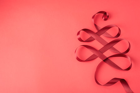 New Year card with Christmas ornament made of red ribbon, festive background. Top view, flat lay, copy space.の写真素材