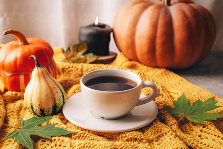 Orange pumpkins, coffee cup and candle on yellow sweater. Autumn still life, Halloween or Thanksgiving conceptの写真素材