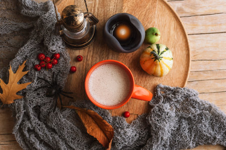 A cup of cappuccino, candles, pumpkin and red berries on wooden tray. Autumn still life. Halloween concept. Top view, flat lay.の写真素材