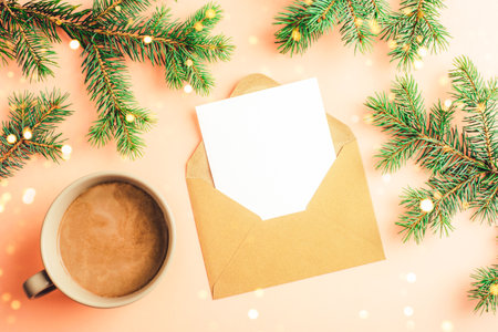 Envelope with blank card and cup with hot drink on pink background with fir branches and golden confetti. Christmas concept. Top view, flat lay, mockupの写真素材
