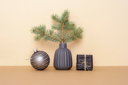 Spruce branch in ceramic vase, gift box and Christmas ball on beige table. Minimal Christmas conceptの写真素材