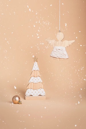 Wooden fir tree toy and angel figurine on neutral beige background. Christmas concept, holiday decorations. Closeupの写真素材