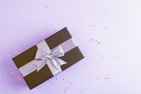 Gift in a box on purple background with confetti. Christmas or birthday, holiday concept. Top view, flat lay, copy space.の写真素材