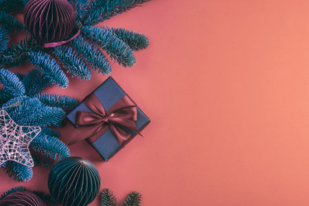 Gift in a black box with bow and fir branches, Christmas baubles on red background. Top view, flat lay, copy space.の写真素材