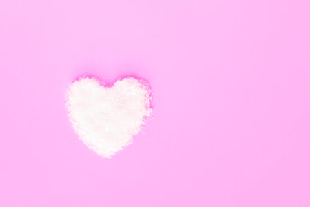 Heart made of snow on yellow background. Valentines day concept. Top view, flat lay.の写真素材