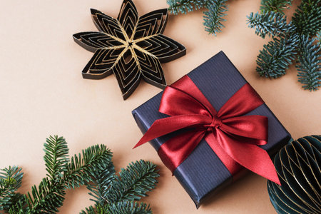 Gift in black box, paper baubles and fir branches on neutral beige background. Christmas concept. Top view, flat layの写真素材