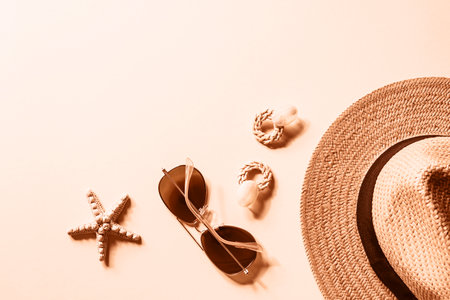 Flat lay with women's summer accessories on neutral background. Sunglasses, straw hat, earrings and starfish. Summer travel concept. Top view, copy space. Color of the Year 2024 Peach Fuzz.の写真素材