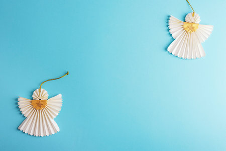 Two Christmas paper angels on light blue background. Holiday concept. Top view, flat lay, copy space.の写真素材
