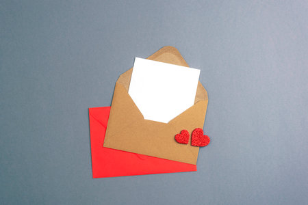 Envelope with blank card and red hearts on gray background. Valentines day concept, top view, flat lay, mockup.の写真素材
