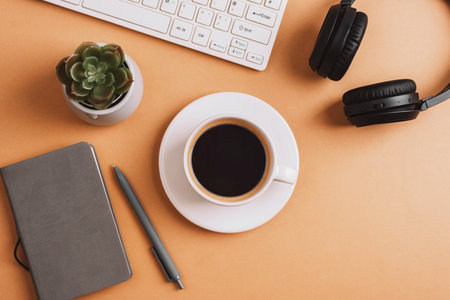 Desktop with coffee cup, notepad, keyboard, succulent plant and headphones on beige table. Top view, flat lay.の写真素材