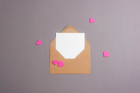 Envelope with blank card and pink hearts on gray background. Valentines day concept, top view, flat...