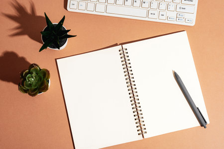 Blank notepad with pen, keyboard and succulent plants with sharp shadows. Top view, flat lay,...