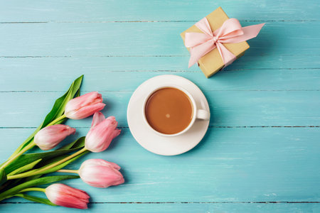 Pink tulips, a cup of coffee and gift in a box on a turquoise wooden table. Spring festive background, top view, flat layの写真素材
