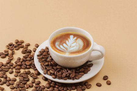 A cup of coffee with coffee art and coffee beans on beige background.の写真素材