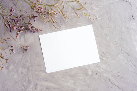 Blank card and kermek flowers on grey concrete background. Top view, flat lay, mockup.の写真素材