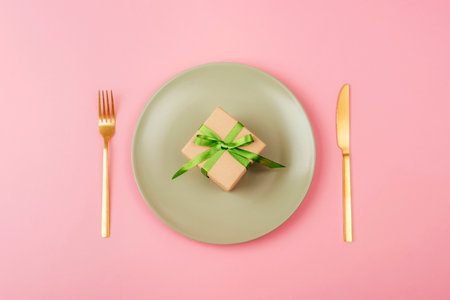 Gift box on light green plate on pink background Mothers day, womens day concept. Top view, flat lay.の写真素材
