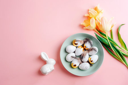 Easter layout with plate of Easter eggs, yellow tulips and bunny on pink table. Top view, flat lay, copy space.の写真素材
