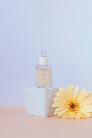 Cosmetic serum bottle on white podium and yellow gerbera flower on a table. Natural skincare concept, closeupの写真素材