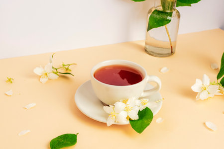 A cup of tea and jasmine flowers on beige table. Closeup.の写真素材