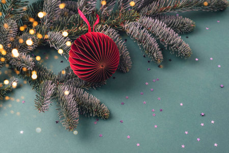 Paper fir tree toy on a branch with golden confetti on green background. Christmas concept. Top view, copy space.の写真素材