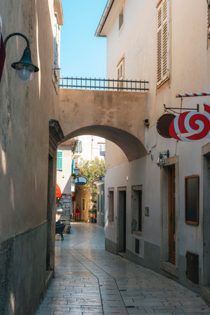 Narrow Street with an Arch and Shop Signs in the Old Town of Krk, Croatiaの写真素材