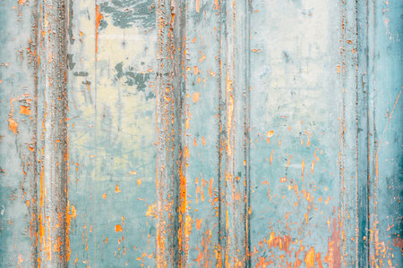 Close-up of weathered turquoise wooden door texture with peeling paint and rustic orange accentsの写真素材