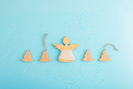 Wooden Christmas trees and angel decorations with confetti on a light blue background, top viewの写真素材