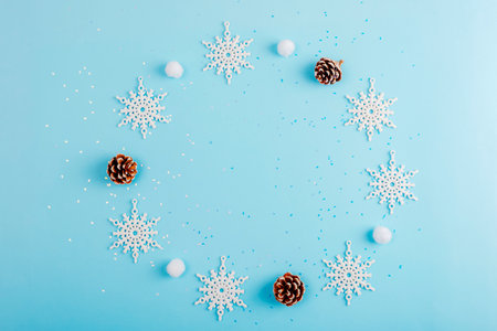 Snowflakes, pinecones, and white balls on a light blue background with scattered glitter flat lay with copy space.の写真素材