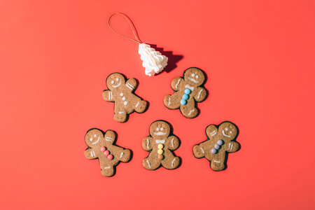 Gingerbread cookies with colorful decorations arranged with festive ornaments on a red background. Top view, flat lay.の写真素材