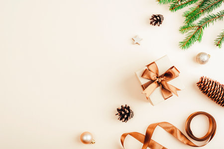 Festive gift box and pine cones on beige background. Top view, copy space.の写真素材