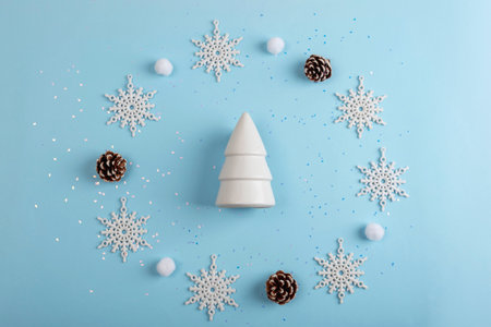 White Christmas tree figurine and snowflakes on blue background. Top view, flat lay, copy space.の写真素材