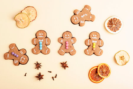 Gingerbread cookies arranged with dried orange and apple slices, star anise and clove on a beige background. Top view, flat lay.の写真素材