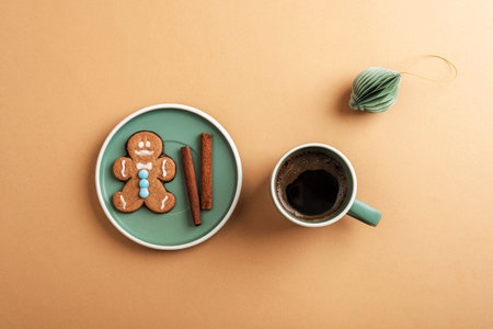 Flat lay of a gingerbread cookie with cinnamon sticks and coffee on a minimalistic beige table. Top view.の写真素材