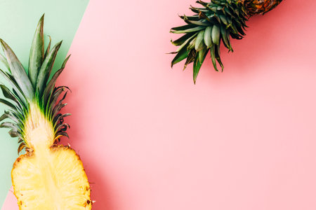 Fresh pineapple half and green leaves styled on pink and green pastel background. Top view, flat lay, copy spaceの写真素材