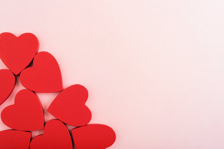 Red wooden hearts arranged on a soft pastel pink background. Valentines day concept. Top view, flat lay, copy space.の写真素材