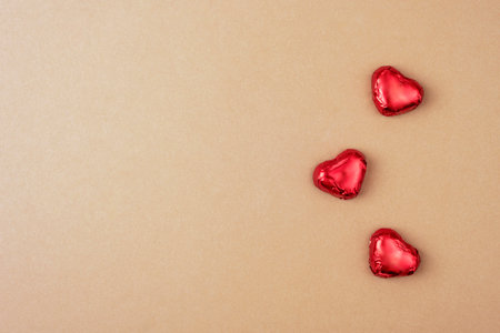 Red hearts candies on a beige surface, symbolizing love and romance in a minimalistic and elegant composition. Valentines day concept. Top view, flat lay, copy space.の写真素材