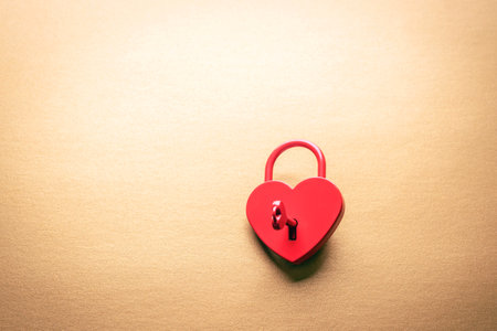 Red heart-shaped padlock with a key on a golden background. Valentines day concept. Top view, flat lay, copy spaceの写真素材
