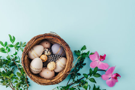 Easter nest with painted eggs, quail eggs, green leaves and pink orchid flowers. Top view, flat lay,...