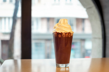 Glass of hot chocolate with whipped cream on cafe tableの写真素材
