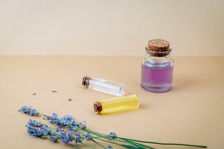 Hydrolat and essential oil bottles with lavender flowers on beige background. Closeup, copy spaceの写真素材