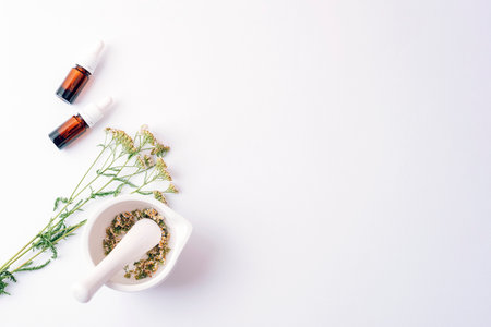 Herbal cosmetic set with essential oil bottles, dried yarrow flowers and mortar on white background. Top view, flat lay, copy spaceの写真素材