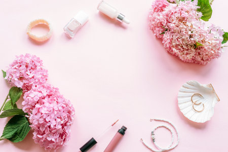 Pink hydrangea flowers with nail polish, lip gloss and jewelry on soft pastel background. Top view, flat lay, copy spaceの写真素材