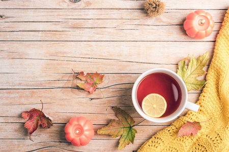 Cup of tea with lemon, candles, leaves and warm knit on rustic wooden table. Autumn concept. Top view, flat lay, copy spaceの写真素材