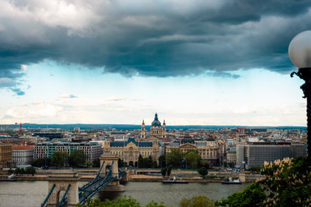 Historic city skyline of Budapest with Chain Bridge over the Danube River under dramatic cloudy skyの写真素材