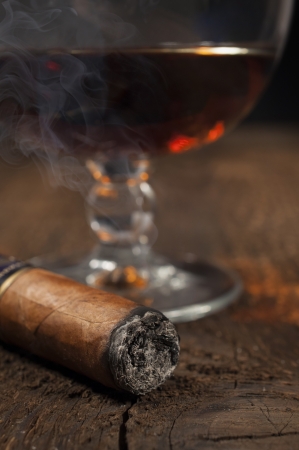  smoking cigar with a glass of brandy in the backgroundの写真素材