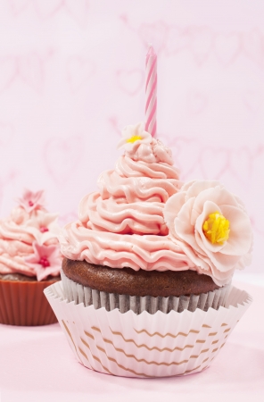 cupcake with pink cream and candle close-upの写真素材