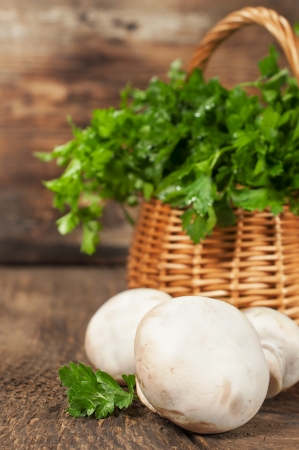 mushrooms and a basket with fresh parsley on wooden backgroundの写真素材
