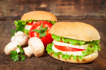 vegetarian sandwich with fresh tomatoes and cheese on wooden backgroundの写真素材
